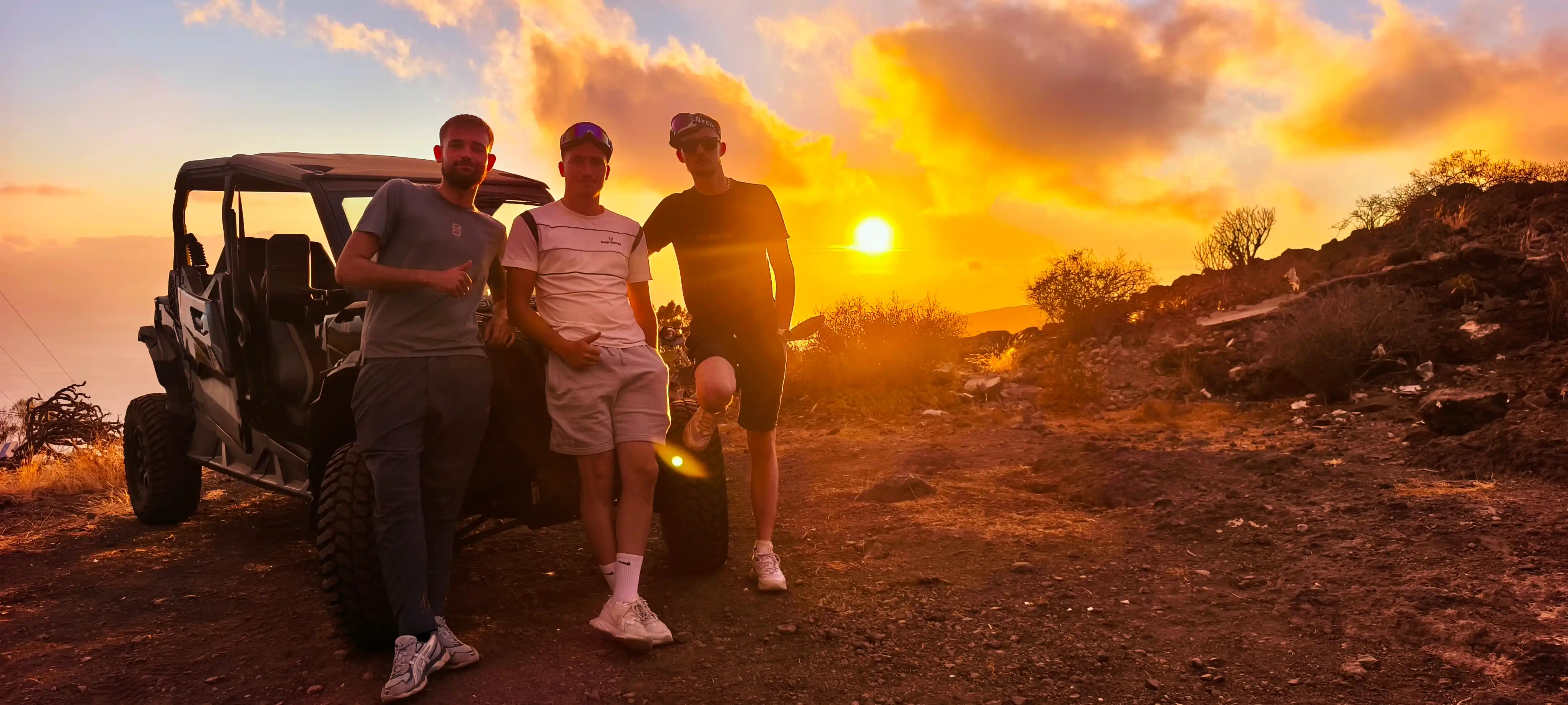 Three people in front of a buggy, with the sun behind them.